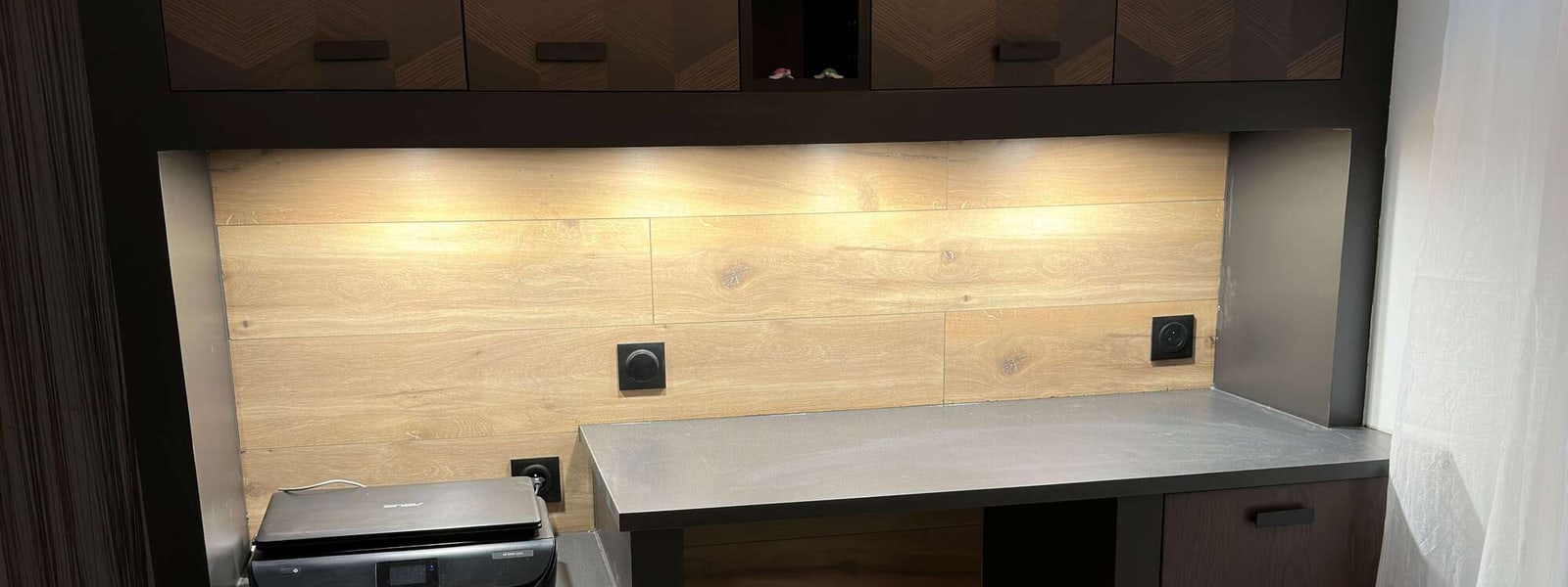Bandeau LED allumé sous un meuble et prise encastrée dans un intérieur fini